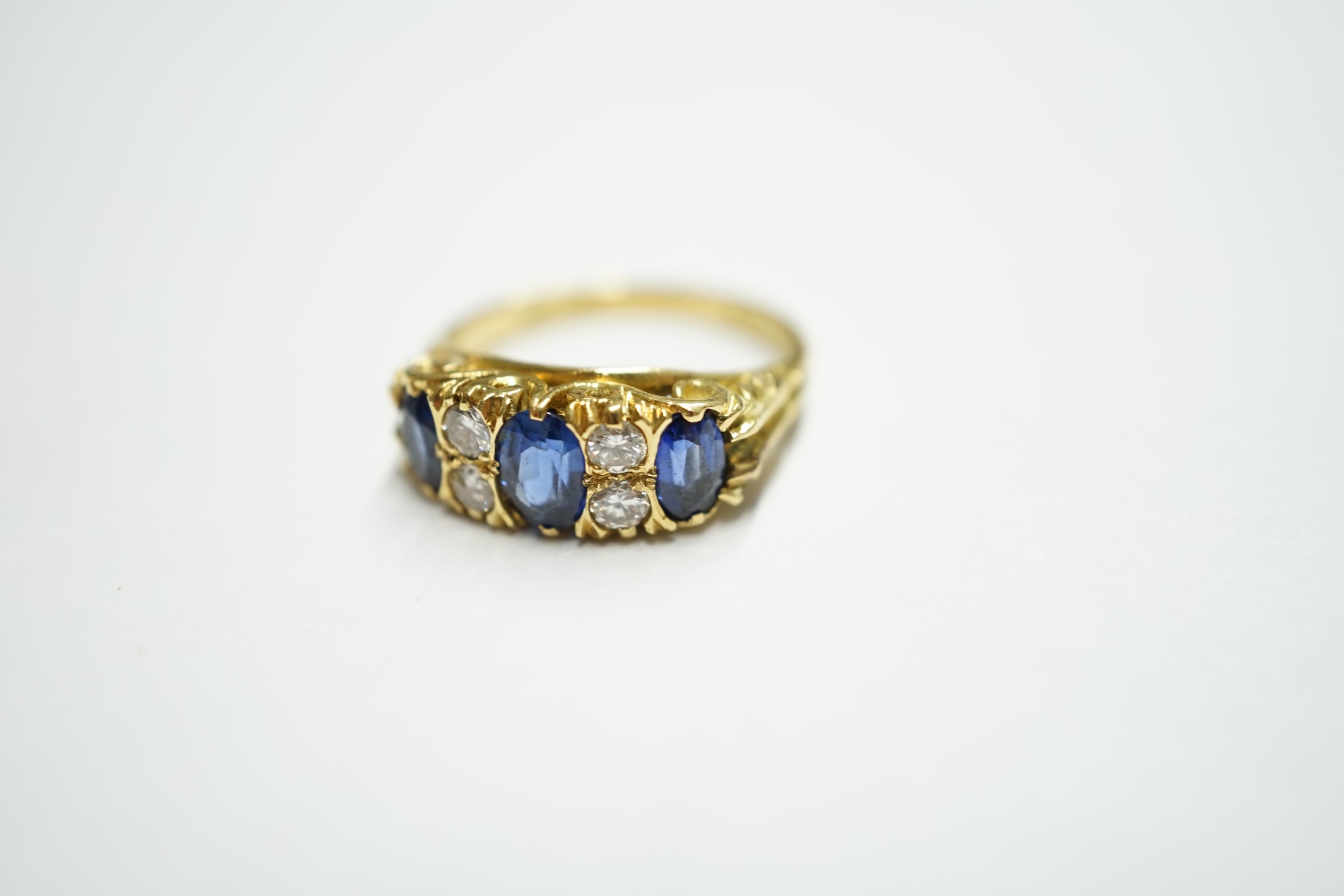 An Edwardian style 18ct gold, three stone sapphire and four stone diamond set half hoop ring, size H, gross weight, 4.9 grams. Condition - fair